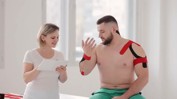 Female therapist explaining medical informations and gives some advice for a patient. Kinesio tapes alt