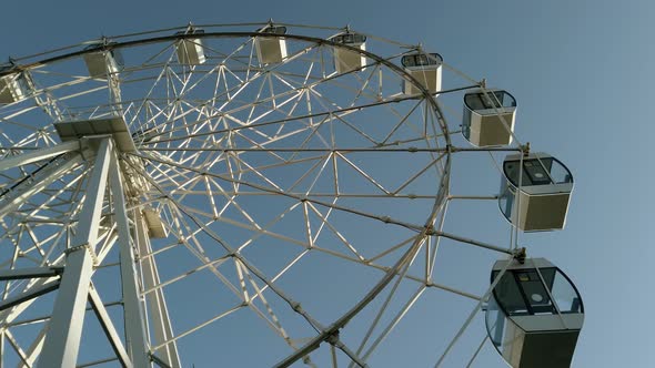 Closeup modern Ferris wheel against blue sky and white clouds alt