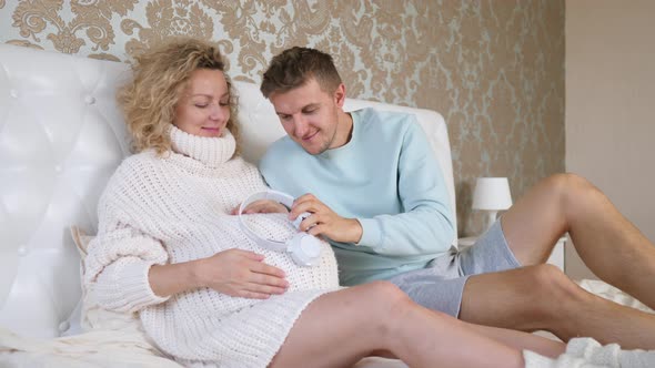 Future Father Putting Headphones On His Pregnant Wife's Belly
