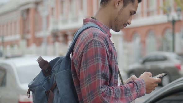 Tourists Asian man using a smartphone checking map while standing beside the street in Thailand.