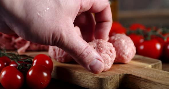 The Man's Hand Put Raw Meatballs on a Cutting Board alt
