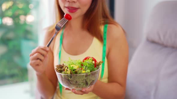 Young woman eating homemade healthy salad at home