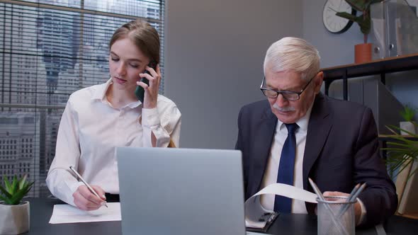 Senior Businessman Company Director Working on Laptop Computer in Office Secretary Talking on Phone alt