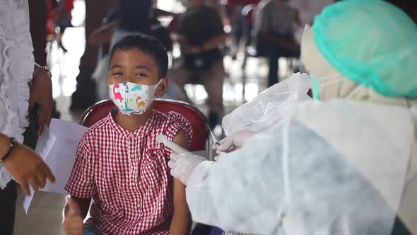 Yogyakarta, Indonesia - Des 20, 2021 : an elementary school boy is receiving the covid-19 vaccine alt