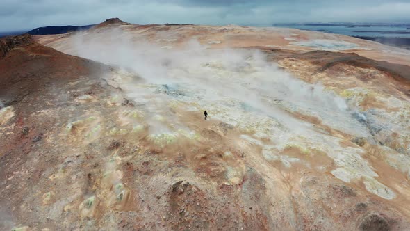Man Walks On Red Mountains in The Hverir Geothermal Area Near Lake Myvatn alt