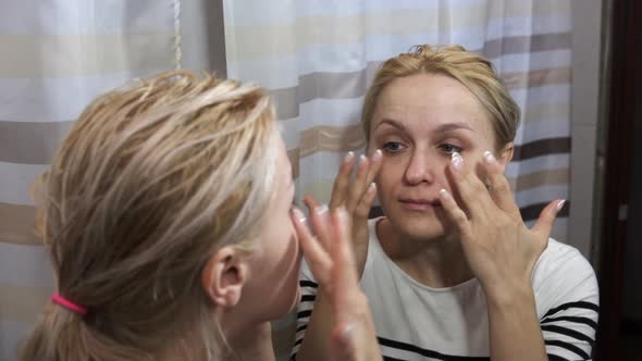 Young woman examining her face in the mirror. Close up.