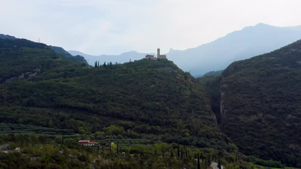 Flying above a valley towards Castello di Drena in Italy