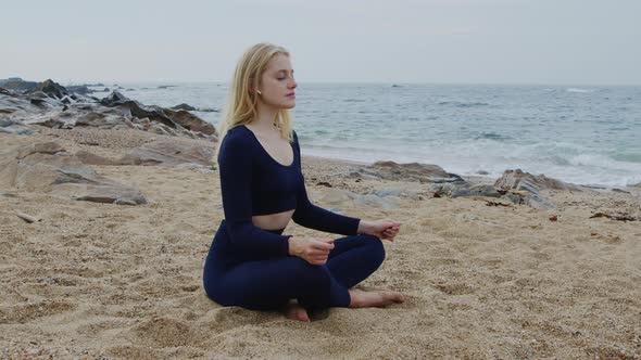 Young Woman Is Practicing Yoga On Beach