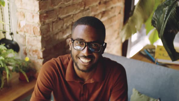 Young Afro-American Man Sitting at Cafe Table and Smiling at Camera alt