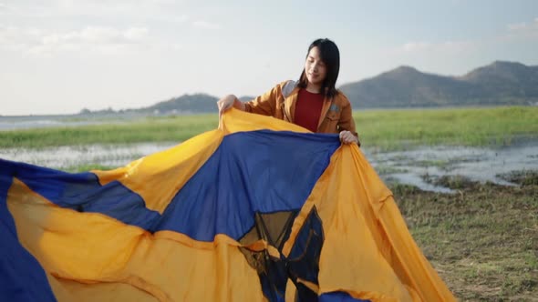 Asian couple campers setting up a camping tent outdoor beside the swamp. alt
