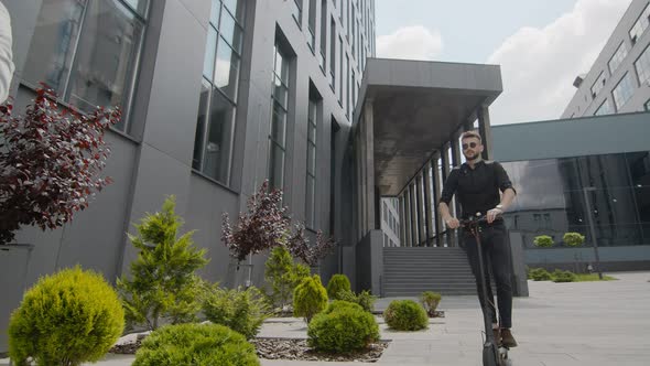 Young Male Businessman Riding on the Transport of the Future Electric Scooter Smiling in the Bright alt