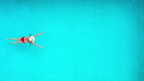 View From the Top As a Woman in Red Swimsuit Swims in the Pool alt