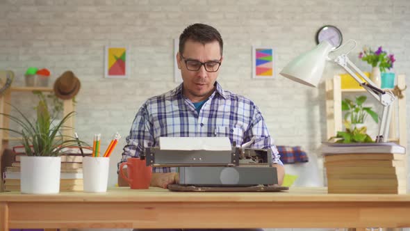 Portrait of Young Man Writer Typing with Inspiration on an Old Typewriter alt