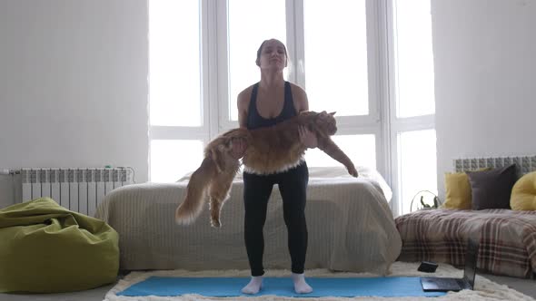 Young Athletic Woman in Sportswear with Cat on Hands Engaged in Fitness at Home