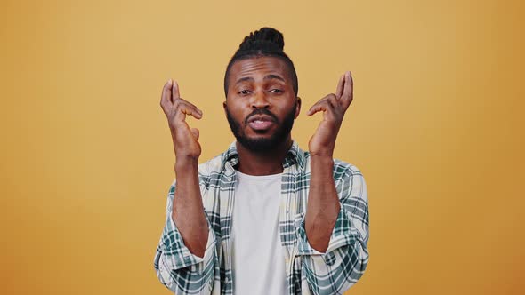 Young Dark Skinned Male Crossing Fingers Acting Like Praying for Luck Showing Thumbs Up and Dancing alt