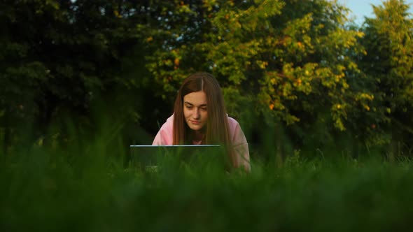Beautiful Young Girl Student Works on a Laptop in a Park Near the University alt