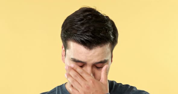 Young man face expressing depressed and disappointed feeling in isolated yellow studio background