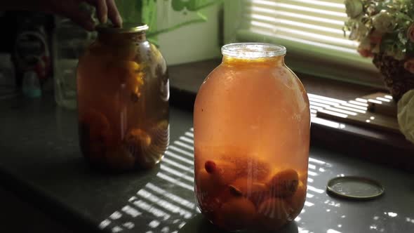 A Man Rolls Up a Jar of Fruit Preserves