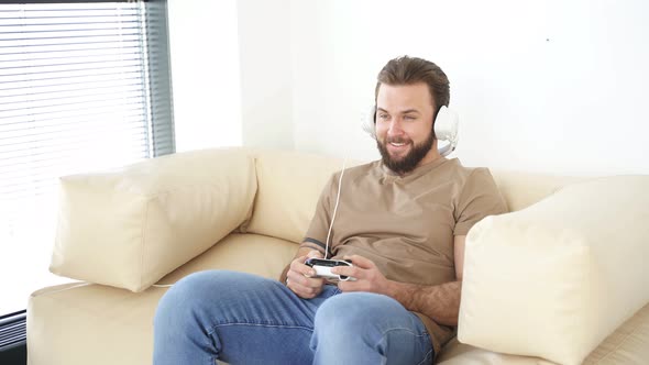 Man Playing Video Game at Home Holding Joysticks in Hands