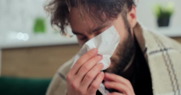 Close Up of the Young Sick Man in the Warm Scarf and a Plaid Blowing His Nose in the Napkin As He alt