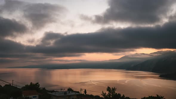 Dramatic and Moody Time Lapse Shot of Sunrise Over Rocky Shore and Calm Sea on Kefalonia Island alt