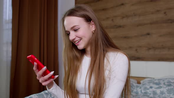Girl Looks at Screen of Mobile Smartphone Makes Successful Online Order Smiles and Looks at Camera alt