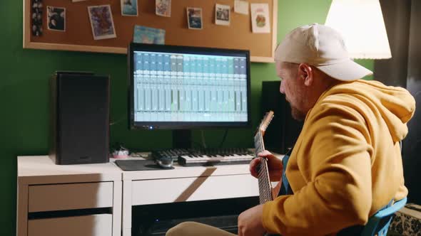 Middleaged Man Playing Guitar and Creating Music Using Equalizer Program alt