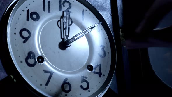 Close up of a  male hand is using the key to the ancient pendulum clock alt