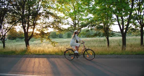 Woman Riding Bicycle on Countryside Road Sunset