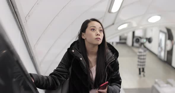 Chinese woman on escalator using smartphone