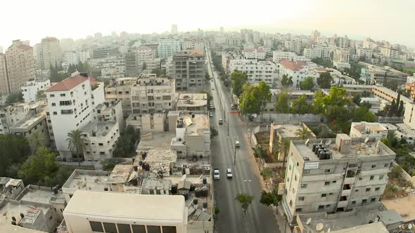 Light traffic on a road in between high rise buildings in Gaza city. alt