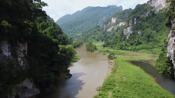 A Tourist Boat Sails Along the River Between Mountains and Green Forests in Asia Around the Jungle