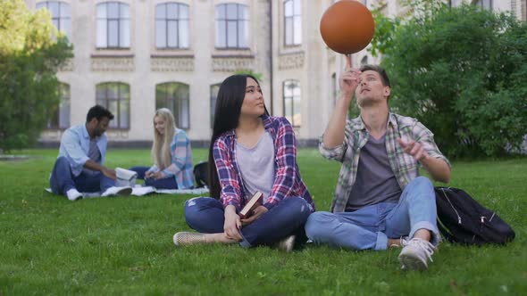 Students Sitting on Lawn on Campus and Flirting, Male Trying to Impress Girl alt
