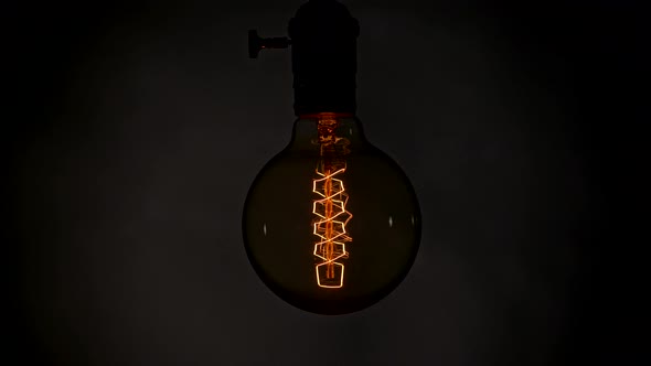 Edison Lamp Blinking and Swinging in a Dark Room During Power Outage alt
