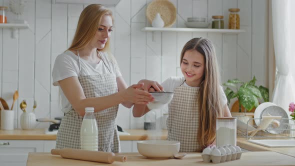 Adult Mother Blonde Woman and Little Daughter Teenager Girl Wear Aprons Learning to Cook Together alt