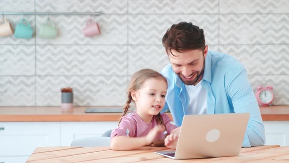 Smiling dad and little daughter talking on an online conference with mom using a laptop alt
