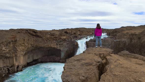 Traveler Hiking at Aldeyjarfoss Waterfall in Iceland alt