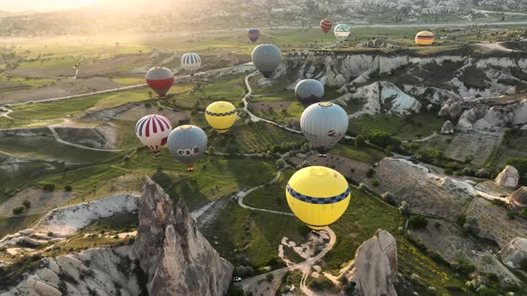 Hot air balloons fly over the mountainous landscape of Cappadocia, Turkey. alt