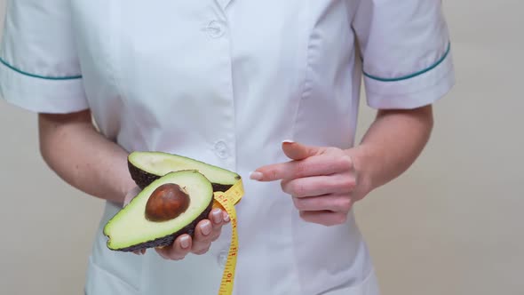 Nutritionist Doctor Healthy Lifestyle Concept - Holding Organic Avocado Fruit and Measuring Tape alt