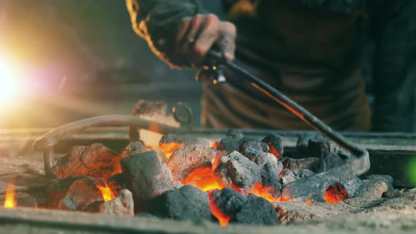 Working Blacksmith Checks Heating Coal. alt