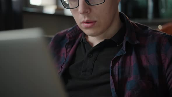 Pensive Serious Man in Glasses Works with Laptop in a Bright Office