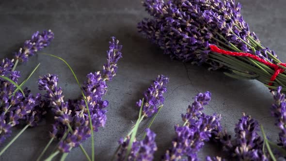 A bouquet of lavender with a red ribbon lies on a gray surface