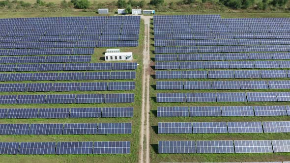 Low aerial reverse flyover over solar panels making up large solar farm ...