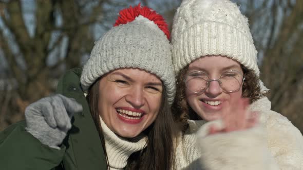 Portrait of Two Cheerful Girlfriends or Sisters on the Background of a Sunny Winter Day alt