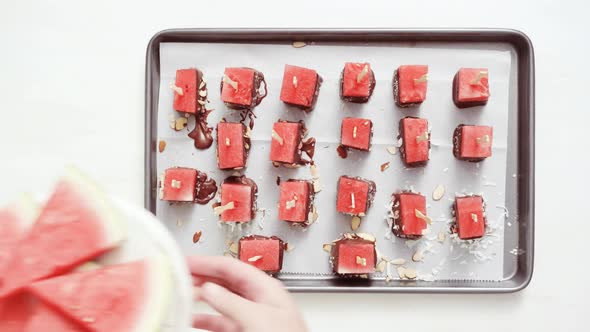 Watermelon cubes into melted chocolate and garnishing with sea salt and almonds cooling on baking sh alt