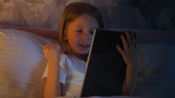 Girl Does Winner Gesture and Presses Key on Tablet in Bed alt
