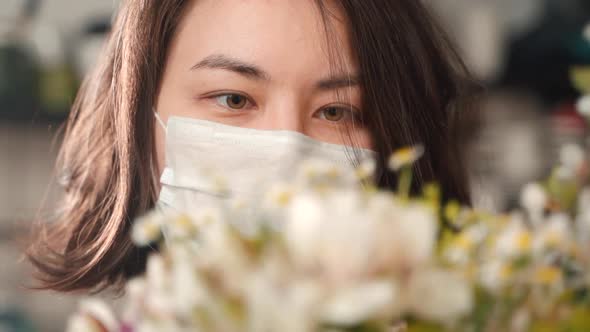 Close Up Portrait of Woman Wearing Protective Mask Working with Flowers. Floristry Business. Asian