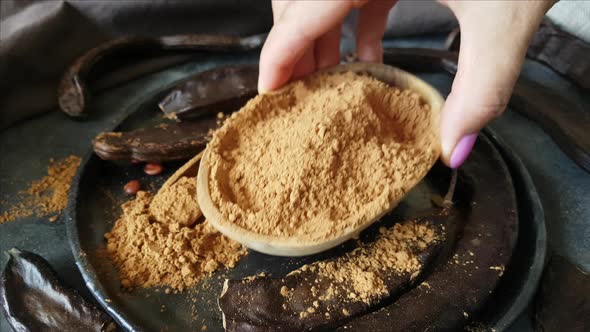 Dry carob pods and powder close up alt
