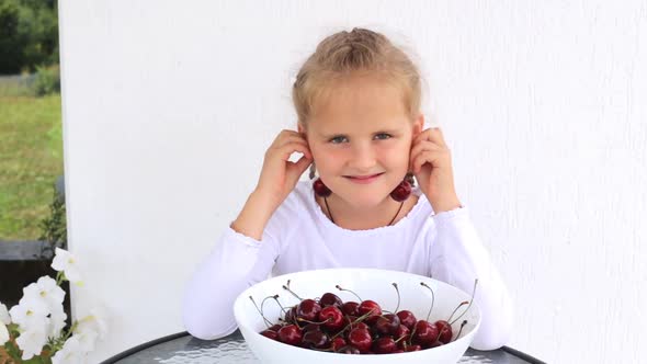 A Girl with Cherries Tries on and Eats Them a Cheerful Mood