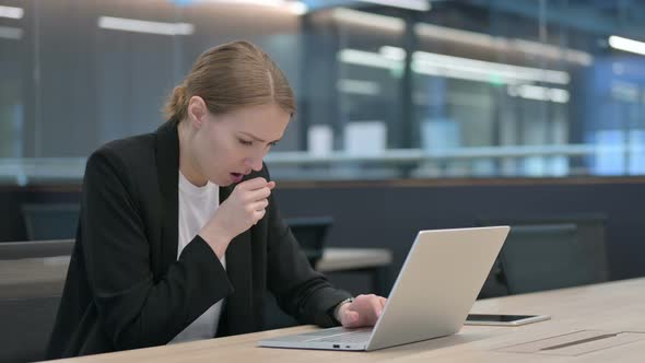 Businesswoman Coughing While Using Laptop at Work alt
